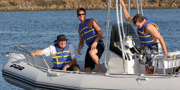 Three people on a boat, wearing life jackets.