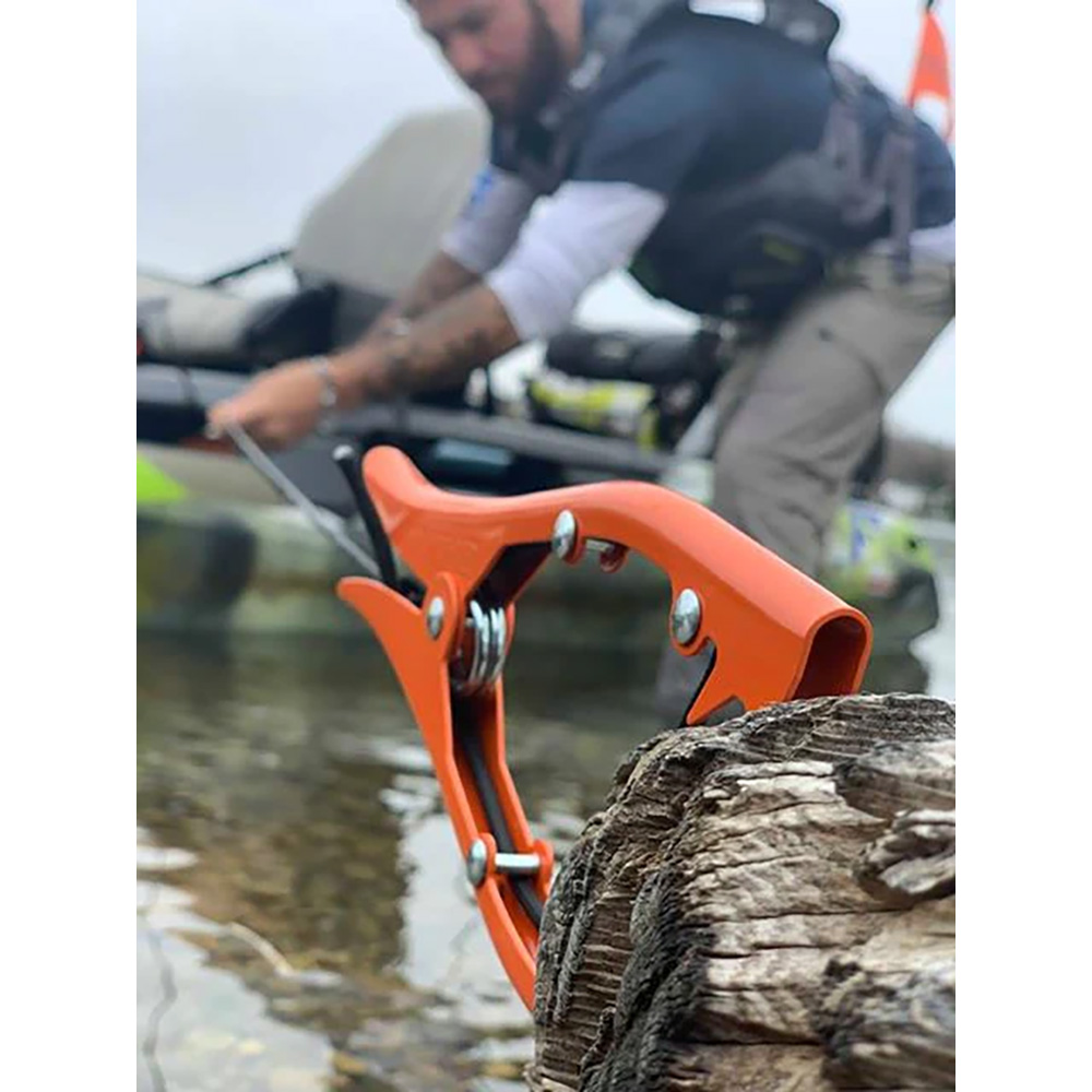 Orange kayak anchor on riverside, person in background.