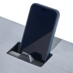 Smartphone charging in desk's built-in holder.