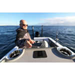 Man on boat holding a smartphone at sea.