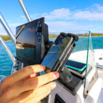 Person using smartphone on boat with navigation screen.