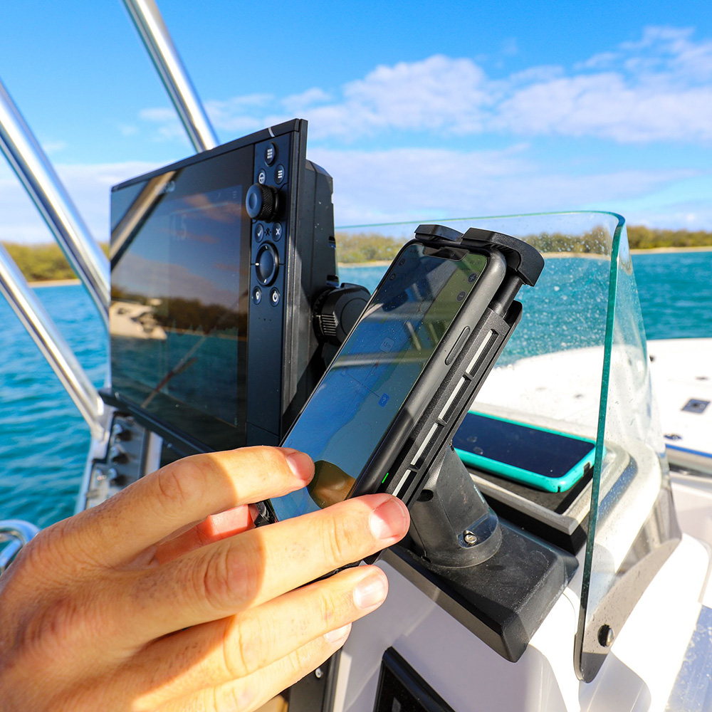 Person using smartphone on boat with navigation screen.
