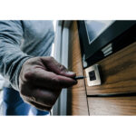 Hand plugging USB cable into wooden wall socket.