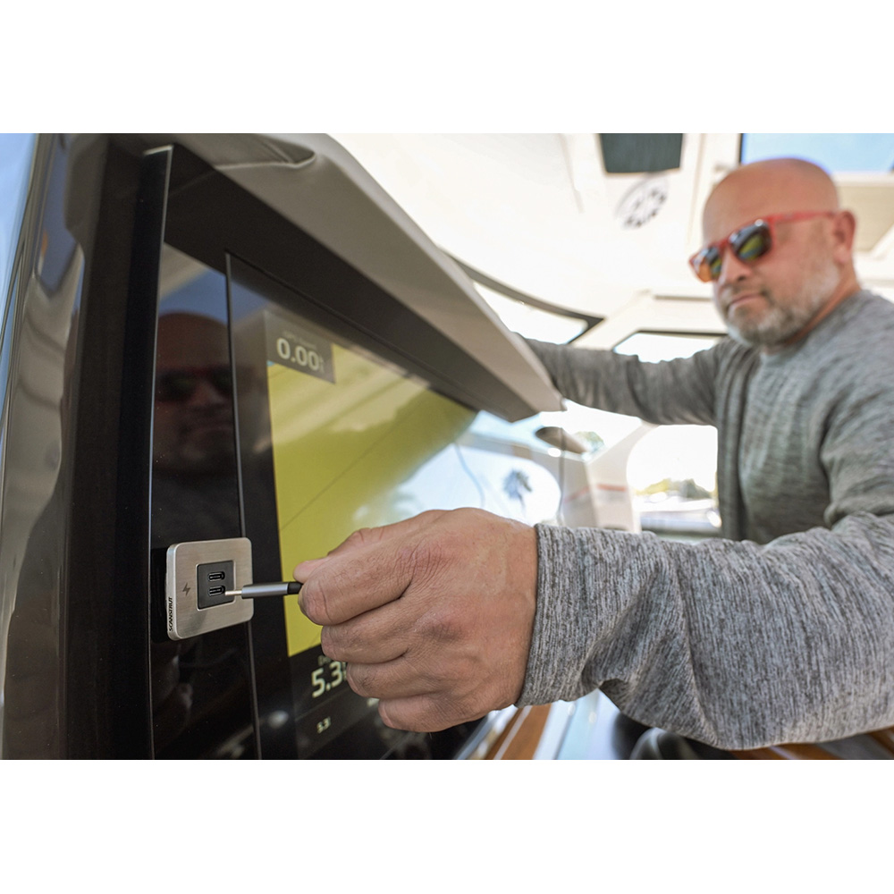Man inserting plug into electronic display on yacht.
