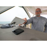 Man using smartphone for wireless charging on boat.