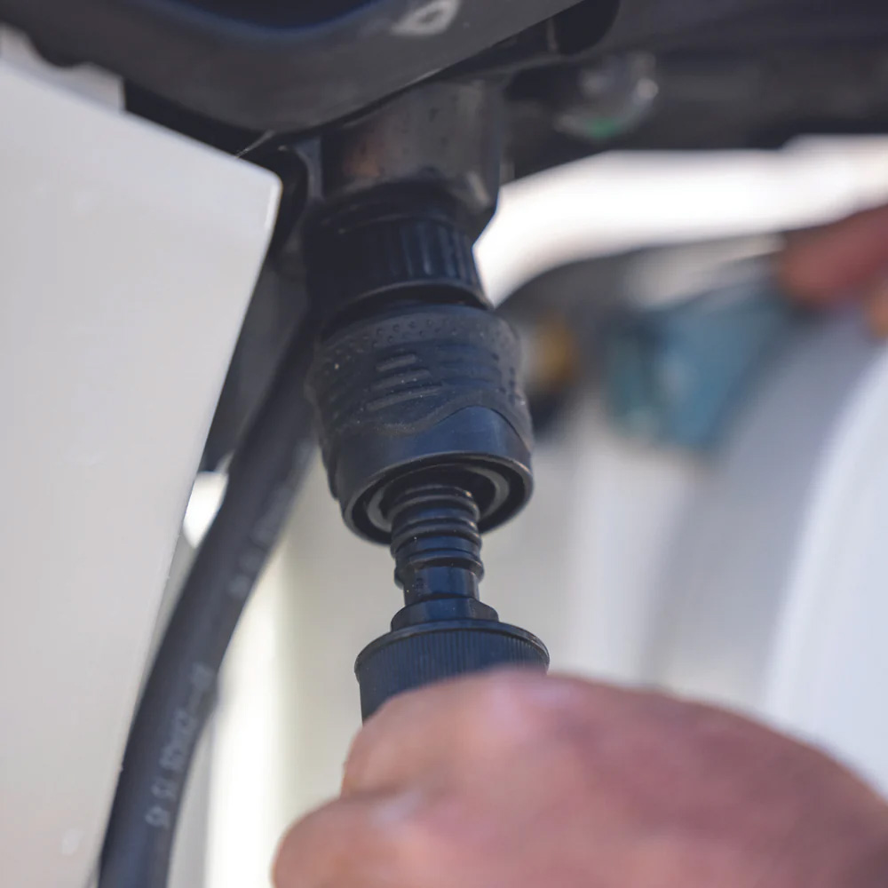 Hand connecting garden hose to water spigot