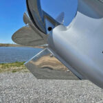 Close-up of shiny boat propeller by the lake.