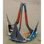 Three metal anchors on sandy beach.
