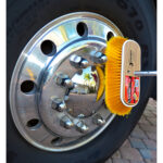 Yellow brush cleaning shiny truck wheel hubcap.