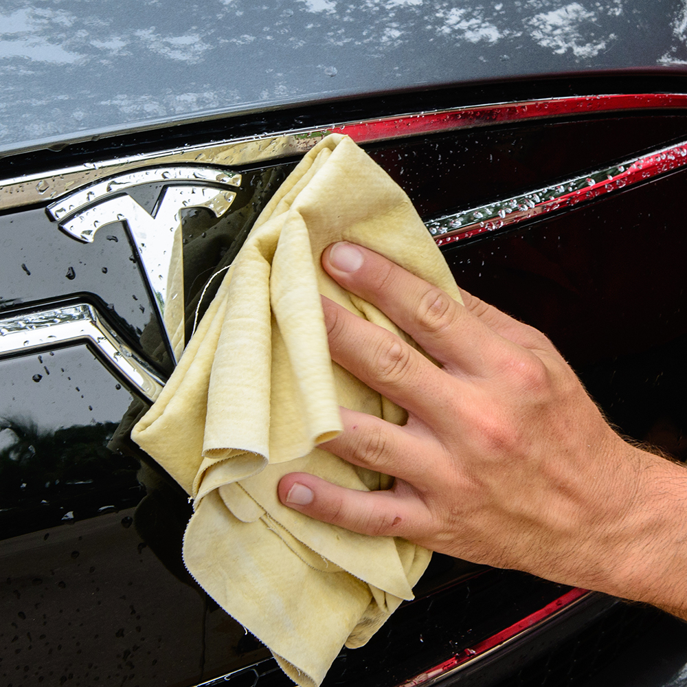 Hand cleaning Tesla car emblem with cloth