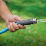 Hand holding garden hose with flowing water