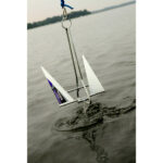 Metal boat anchor entering water on a lake.