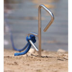 Metal stake with blue rope on beach.