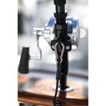 Fishing reel with attached carabiner and coiled lanyard.