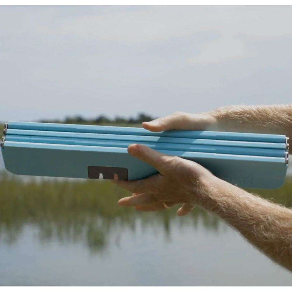 Person holding blue folding chair outdoors.