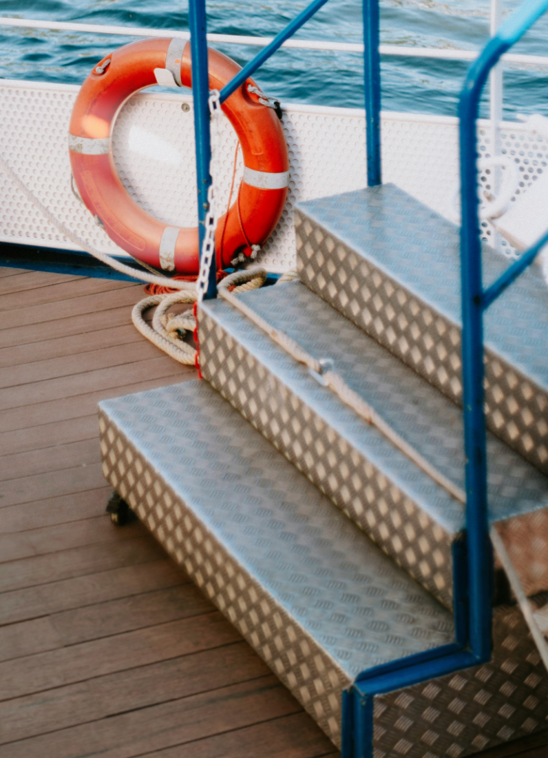 Boat deck with life preserver and metal stairs.