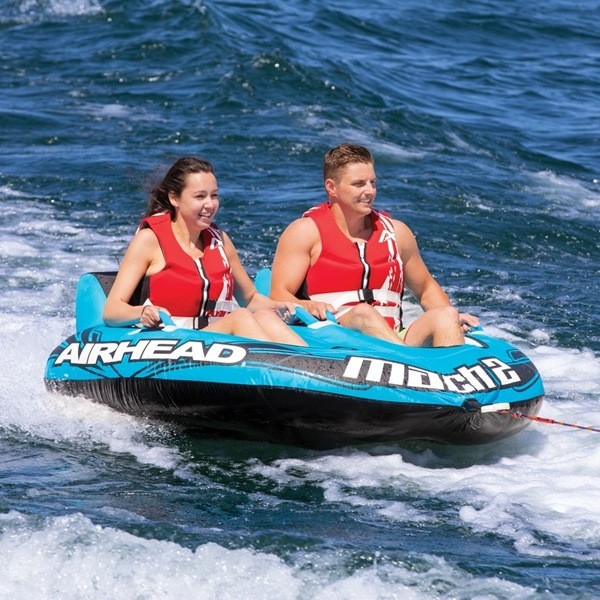 Two people riding inflatable tube on ocean