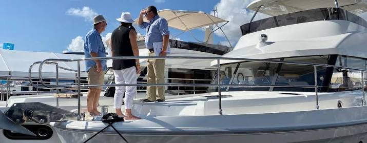 Three people stand on deck of a luxury yacht